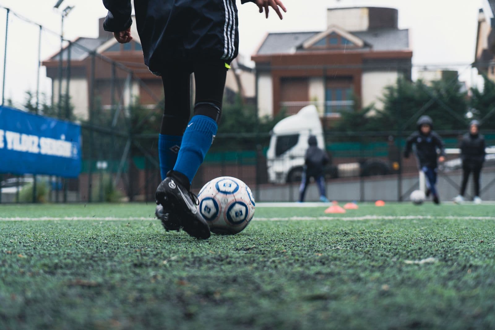 A young player's boots and the ball, mid-drill on a training pitch